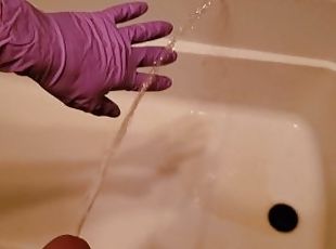 Holding his peeing cock with rubber gloves